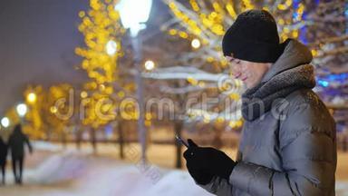 一个十几岁的孩子在雪夜街使用智能手机